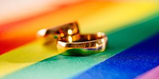Zwei goldene Eheringe auf einer Regenbogenflagge