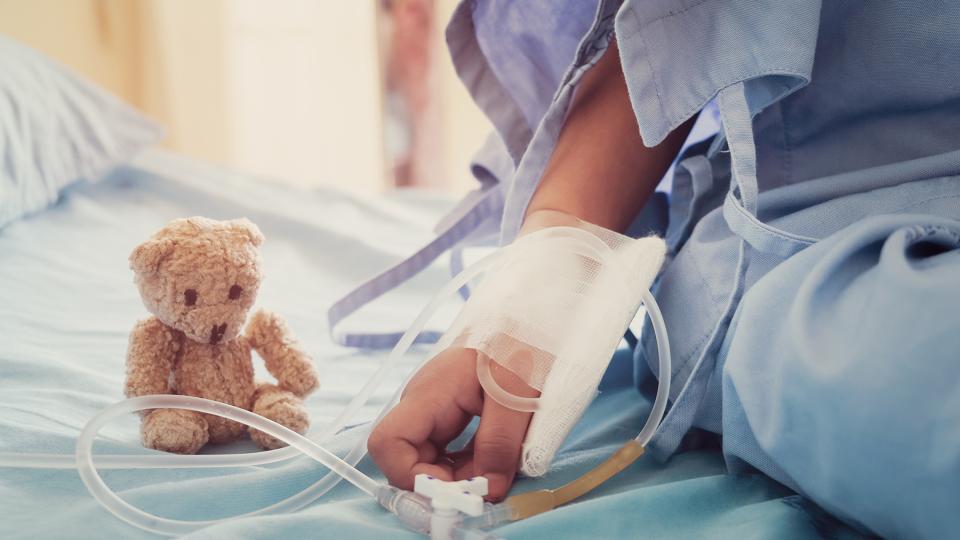 Kind mit Infusionsschläuchen in einem Krankenhausbett