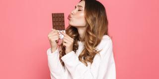 Eine junge Frau küsst eine Tafel Schokolade