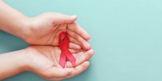 Rote Schleife der Deutschen AIDS-Stiftung in offenen Händen