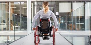 Frau im Rollstuhl im behindertengerechten Bürohaus