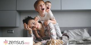Erschöofte Mutter mit zwei kleinen Kindern, die um sie toben