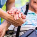 Eine Pflegerin drückt die Hände einer Pflegebedürftigen
