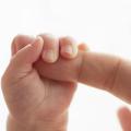 Babyhand umklammert den Finger eines Erwachsenen