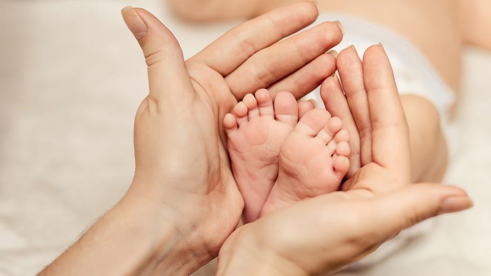 Mutter hält die Füßchen eines Neugeborenen in den Händen